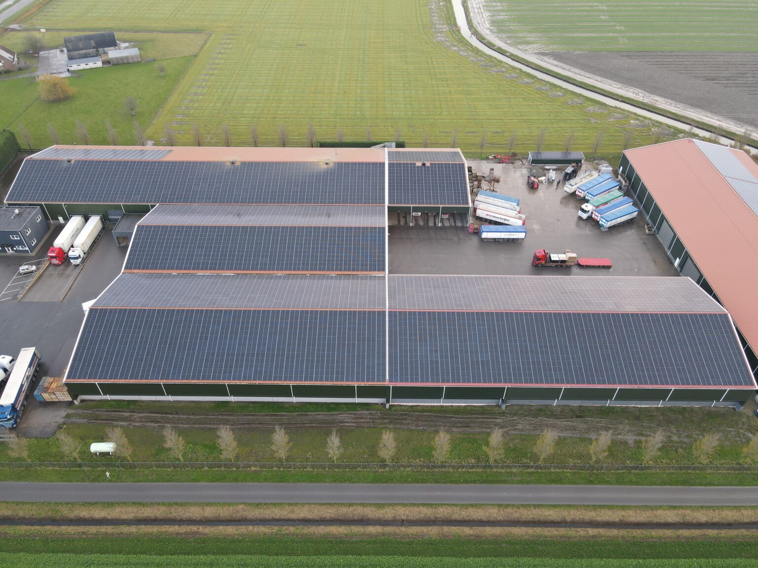 Luchtfoto van een agrarisch bedrijf in de polder met daken vol zonnepanelen van Gebar GO